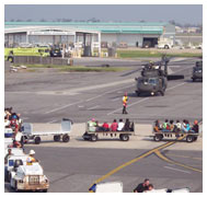 Luggage cars transport patients to helicopters waiting on airport runway