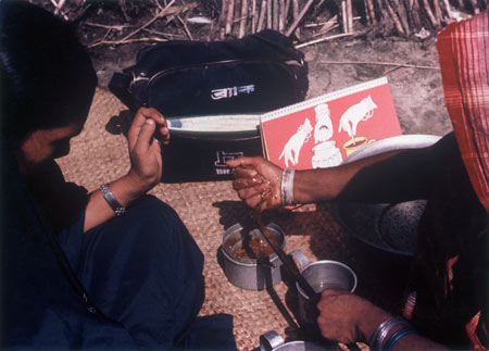 Village woman measures ingredients with fist while BRAC teacher observes