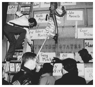 Vigil participants hang signs with names on building wall