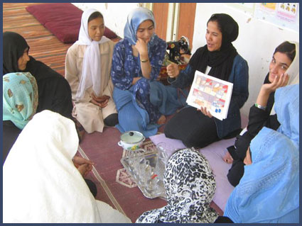 BRAC community health worker shows illustration chart to a group of women