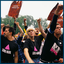 ACT UP members shout protests and hold placards.