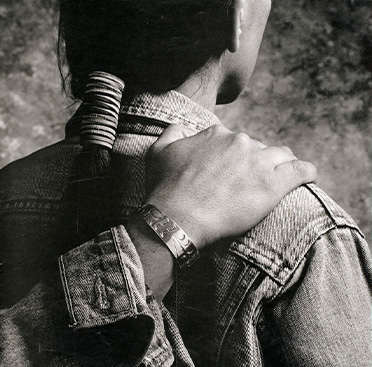 A poster with text and a black and white photograph of a hand resting on the shoulder of a Native American man who is facing away from the viewer