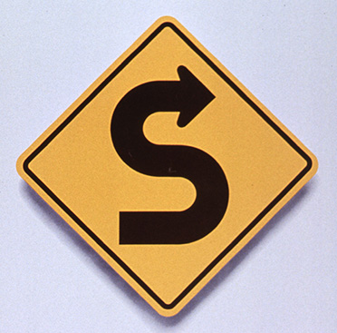 Yellow square road sign that has black curved arrow indicating curves in the roadway ahead above text