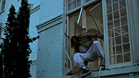 A Native American man escaping a building from a window.