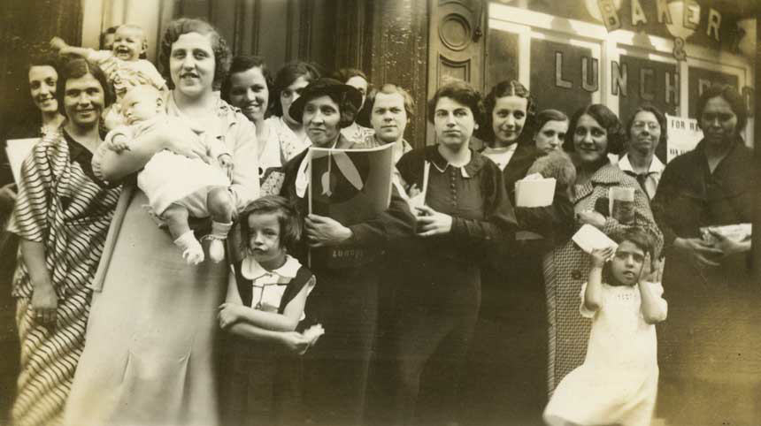 16 White immigrant women and children stand with White female nurse.