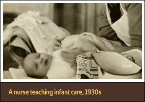 White female nurse stands over a baby lying on a table.