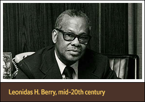 African American man (Leonidas Berry) seated at desk and looking at viewer.