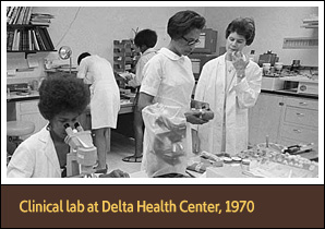 7 White and African American men and women in laboratory, some working and some talking.