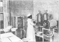 A Native American female nurse stands in an operating room. Sherman Institute, Riverside, Cal., c. 1916. Souvenir album of a California off-reservation Indian school.