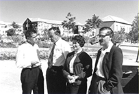 Three white men and one white woman stand together outdoors.