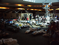 Patients lay on gurneys, wrapped in blankets in a lobby with health workers in the background.