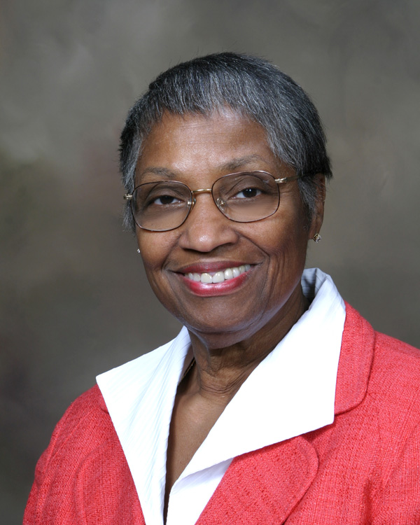 A woman’s portrait wearing glasses and a red jacket with a white shirt.