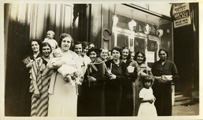 Fourteen women posing as a group, one holding a baby and one with a child in front.