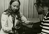 White woman in lab coat checks blood pressure of White patient.