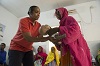 African America woman hands an infant sized mannequin to an African woman.