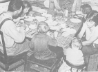 Overhead view of a family of six sitting at a table and eating a meal.