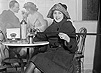 Woman sitting in café pouring alcohol into her glass from a hollowed out cane.