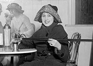 Woman sitting in café pouring alcohol into her glass from a hollowed out cane.