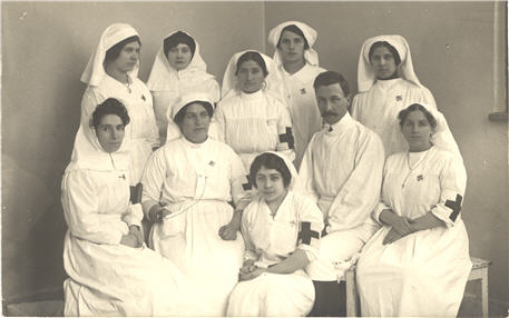 Group of nine White nurses and a White doctor in white uniforms.