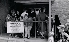 People stand in line outside of a building