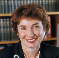 Dr. Marcia Angell, a White female in a dark suit jacket and pearls with bookshelves behind her.