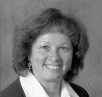 Dr. Nereida Correa, a smiling White female in a collared shirt and sweater posing for her portrait.