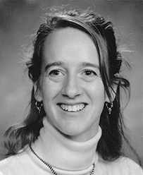 Dr. Angela M. Erdich, a young female wearing a turtleneck and earrings posing for her portrait.