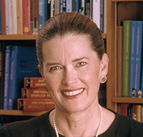 Dr. Jane Ellen Henney, a smiling White female wearing pearls seated in front of book shelves.