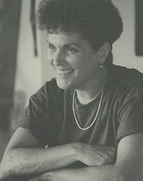 Dr. Elizabeth Karlin, a female with curly hair, posing with her arms folded in front of her for her portrait.