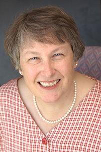 Dr. Mary Modelle Newman, a smiling White female in pearls and red checkered blouse.