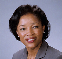 Dr. Elizabeth Ofili, a smiling African American female in a suit and pearls posing for her portrait.