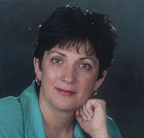 Dr. Frances Owl-Smith, a White female with short hair wearing a teal blouse posing for her portrait.