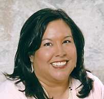 Dr. Conchita Marie Paz, a smiling Hispanic female with dark hair and a pink sweater posing for her portrait.