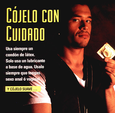 A Latino man stands holding a condom