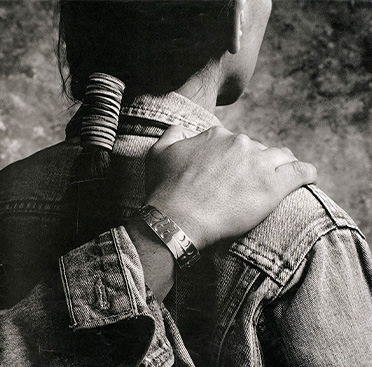 A poster with text and a black and white photograph of a hand resting on the shoulder of a Native American man who is facing away from the viewer