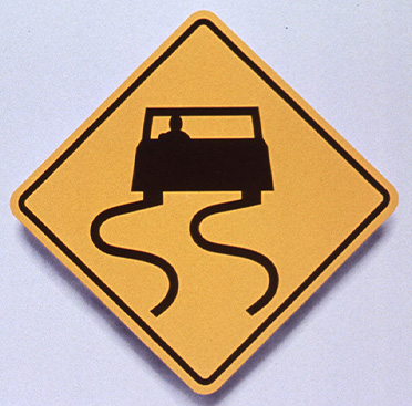 Yellow square road sign that has black outline of car with curved lines behind it indicating curves in the roadway ahead above text