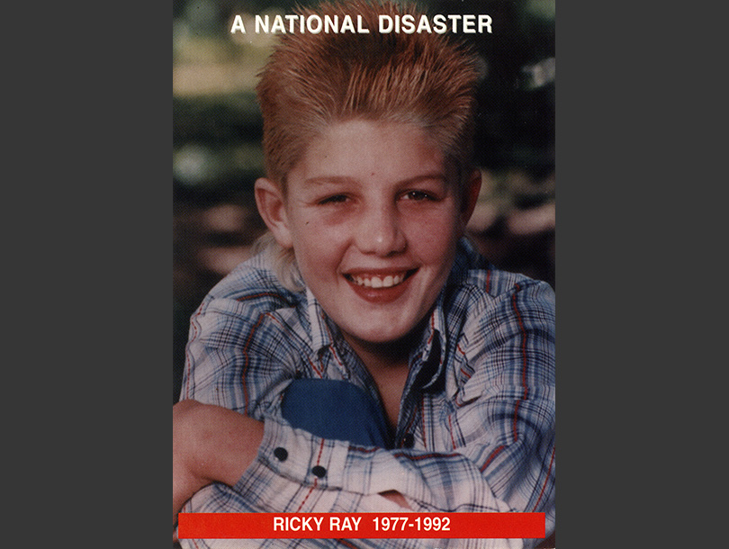 Color photograph of a smiling white boy (Ricky Ray) sitting in the grass