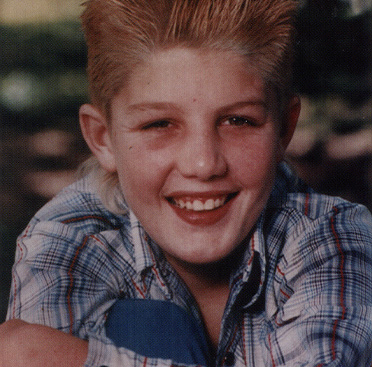 Color photograph of a smiling white boy (Ricky Ray) sitting in the grass