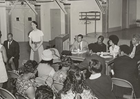 A white woman speaks to a roomful of people