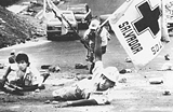 Three aid workers taking cover on the street and waving a flag