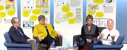 Three women and a man sit in a group in front of a banner display.