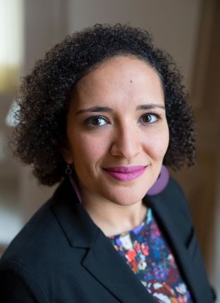 Photograph of a woman in a black blazer and abstract pattern top