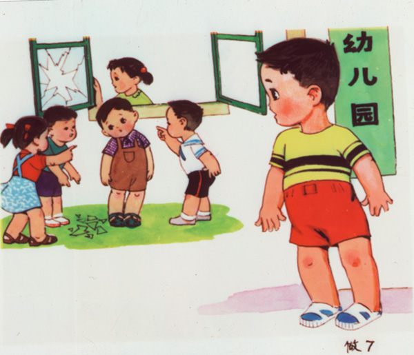 Slide showing a little boy with dark hair, wearing red shorts and a yellow and black shirt, standing apart from a group of children who are pointing at another boy, in brown overalls and checkered shirt; they appear to be accusing him, a smashed window is shown in the background